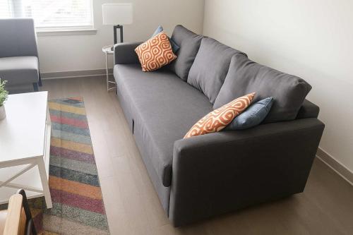 a gray couch in a living room with pillows on it at Stunning Nulu 1BR CozySuites 01 in Louisville