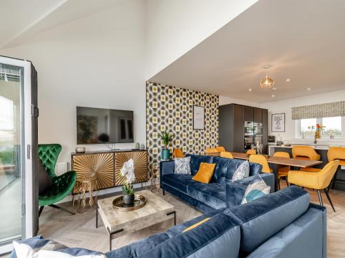 a living room with blue couches and yellow chairs at Sandbanks in Bridlington