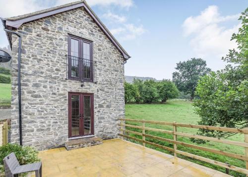 an exterior view of a stone house with a fence at Sgubor Fach in Pen-y-bont-fawr