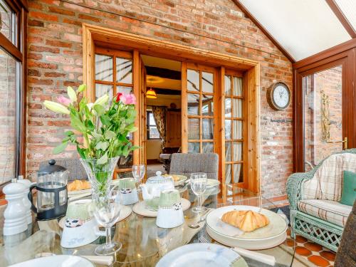 a dining room with a glass table with flowers on it at The Pigsty - Uk30945 in Barthomley
