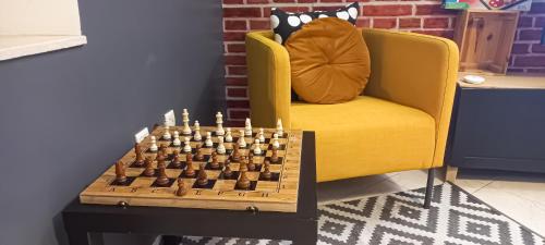 a chess board on a table next to a yellow chair at Budget-Friendly Apartment Near AirPort in Nouaseur