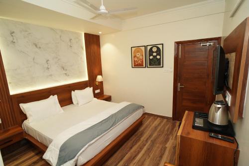 a hotel room with a bed and a television at Hotel Premjees Paradise in Solan
