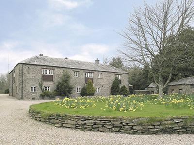 a large stone house with a stone wall and flowers at The Shooting Lodge in Saint Mabyn