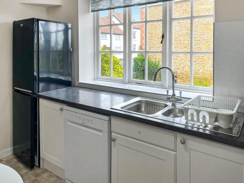 a kitchen with a sink and a black refrigerator at The Loft in Ilminster