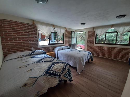 a bedroom with two beds and a brick wall at Cabaña La Hacienda 1 in Mineral del Chico
