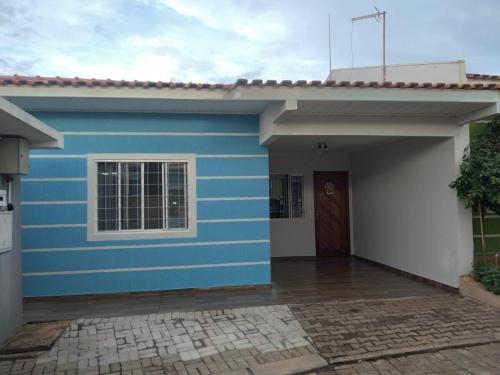a blue and white house with a door at Casa em condomío, ótima localização in Cascavel