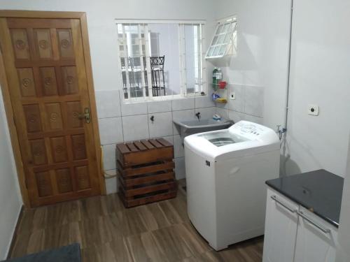 une petite cuisine avec un évier et une machine à laver dans l'établissement Casa em condomío, bem localizada, à Cascavel