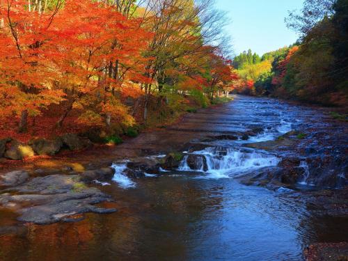 a river with fall leaves and a waterfall at Grids Premium Hotel Kumamoto in Kumamoto