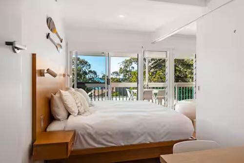 a bedroom with a large white bed and windows at Seaviews Little Cove Beach Noosa 2BR 200m to beach in Noosa Heads