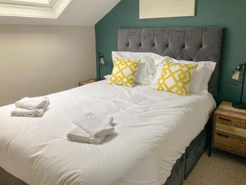 Un dormitorio con una gran cama blanca con toallas. en Snowdon House, en Porthmadog