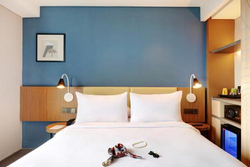a bedroom with a large bed with a blue wall at ibis Styles Bogor Pajajaran in Bogor