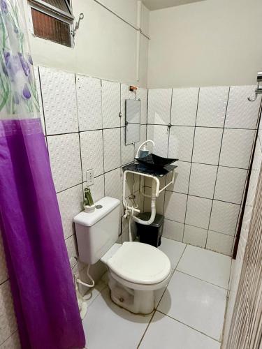 a bathroom with a toilet and a purple shower curtain at Pousada Praiana Jericoacora in Jericoacoara