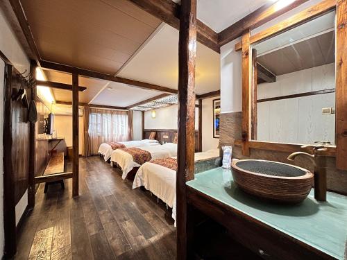 a room with two beds and a bathroom with a sink at 张家界畔山驿栈 in Zhangjiajie