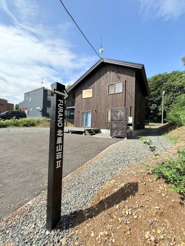 a sign on a pole in front of a building at furano Hokuseisanso II in Wada
