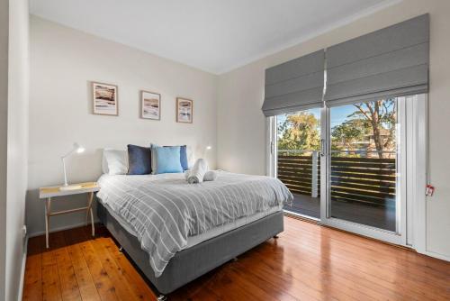 Un dormitorio con una cama y una ventana grande. en The Dolphin Beach House, en Vincentia