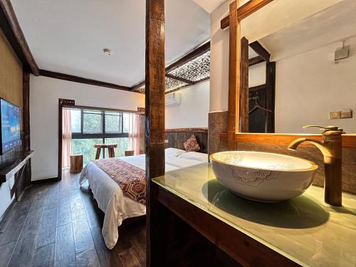 a bathroom with a sink and a bed in a room at 张家界畔山驿栈 in Zhangjiajie