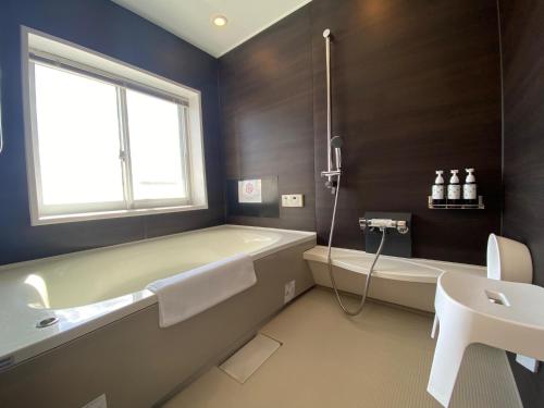 a bathroom with a tub and a toilet and a sink at Empire Skyridge Hotel - Vacation STAY 17783 in Chikugo