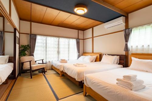 una habitación de hotel con 3 camas y una silla en Hatsune 観光拠点 多人数向け 閑静な住宅街, en Otaru