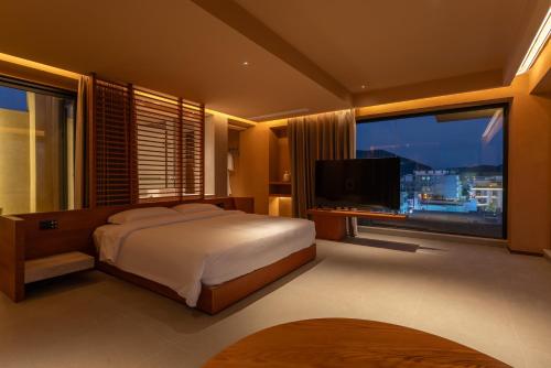 a bedroom with a bed and a flat screen tv at Roy Hotel-Tianya Town Store in Sanya