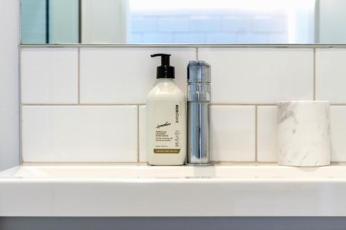 a bathroom sink with a bottle of soap and a window at Central Christchurch Apartment with Parking in Christchurch