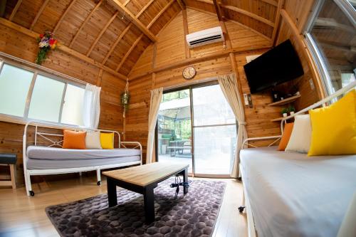 a room with two beds and a tv and a table at Kozakura Cottage 小桜コテージ in Kuma