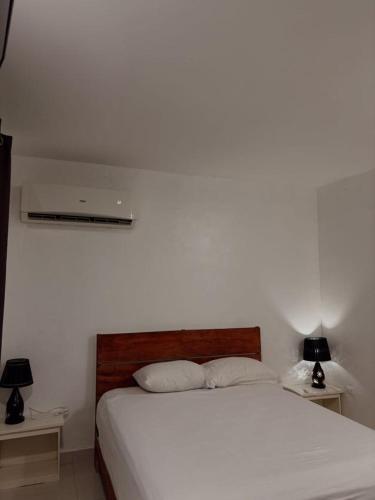 a bedroom with a white bed and two night stands at Hostel Gato Colonial in Santo Domingo
