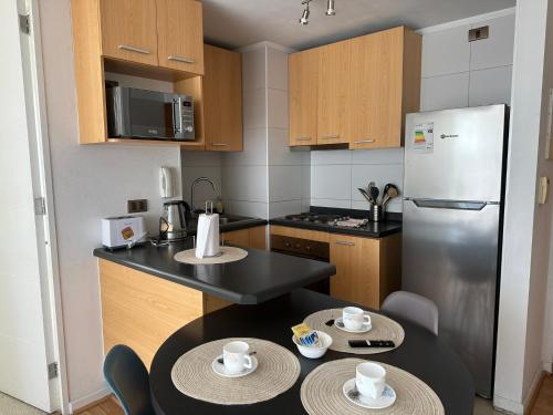 a kitchen with a stainless steel refrigerator and two tables at Dpto 2 dormitorios Cercano Aeropuerto, Concepción in Concepción
