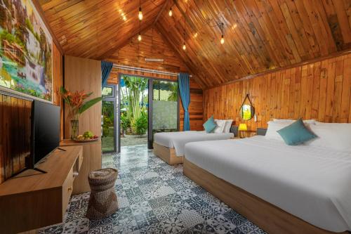 a bedroom with two beds and a flat screen tv at Tam Coc Forest Bungalow & Spa in Ninh Binh