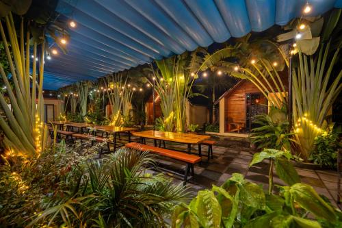 a patio with tables and benches in a garden with lights at Tam Coc Forest Bungalow & Spa in Ninh Binh
