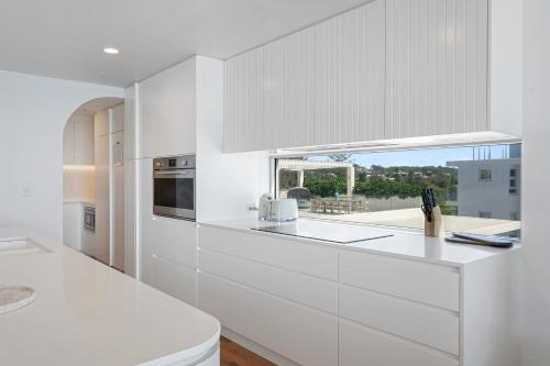 a white kitchen with a counter and a window at Beachfront Penthouse with Private Rooftop, BBQ, 2Car in Gold Coast