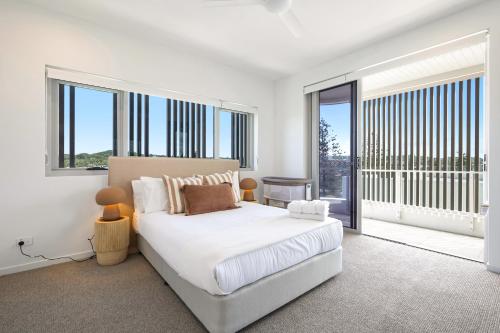 a white bedroom with a bed and large windows at Beachfront Penthouse with Private Rooftop, BBQ, 2Car in Gold Coast
