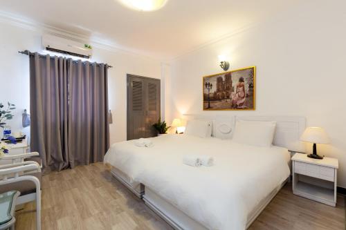 a white bedroom with a large white bed and a chair at Premium Hotel Saigon - Ben Thanh Market in Ho Chi Minh City