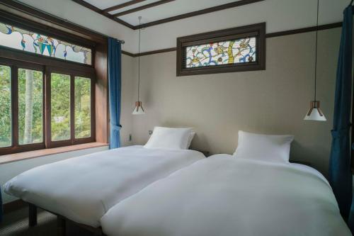 two beds in a room with two windows at Ochiairo in Izu