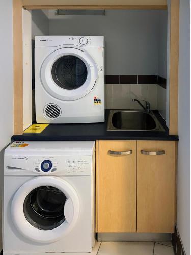 a kitchen with a washing machine and a sink at Caloundra Central Apartment Hotel Official in Caloundra