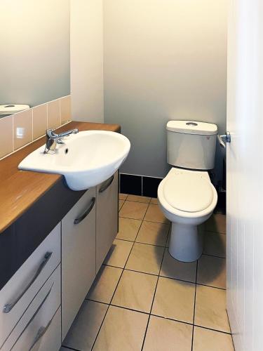 a bathroom with a white sink and a toilet at Caloundra Central Apartment Hotel Official in Caloundra