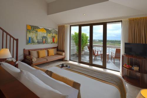 a living room with a couch and a large window at RiverTown Hoi An Resort & Spa in Hoi An
