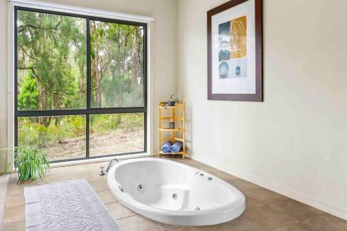 a bath tub in a room with a large window at Otway Estate Cabins in Barongarook