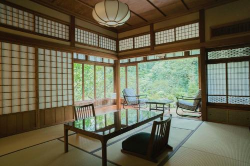 a room with a table and chairs and windows at Ochiairo in Izu