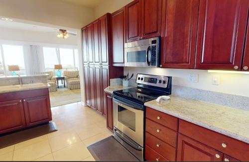 a kitchen with wooden cabinets and a stove top oven at ❤PiH❤MAJESTIC OCEANOcean Views Stunning Mauna Kea Resort Best Beaches Bikes in Hapuna Beach