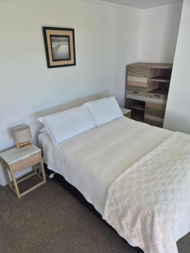 a bedroom with a bed and a side table at Bronny's Beachfront BnB in Whitianga