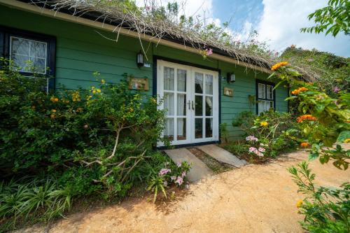 a green house with a white door and some flowers at Huha's Farmstay Đà Lạt in Lạc Dương