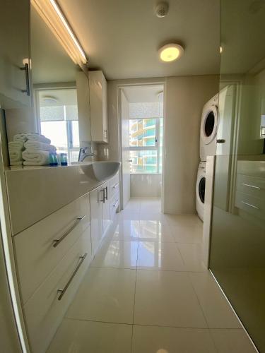a white kitchen with a sink and a washing machine at One The Esplanade Apartments on Surfers Paradise in Gold Coast