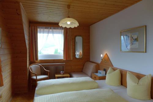 a bedroom with two beds and a chair and a window at Haus Salzburgerland in Mauterndorf