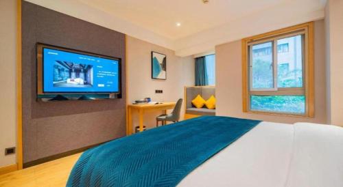 a bedroom with a large bed and a tv on a wall at Xian Katie Eastman Hotel in Xi'an