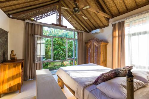 um quarto com uma cama e uma grande janela em BoHo Bingin Beach Bali em Uluwatu