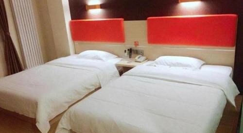 two beds in a hotel room with a telephone at 7 Days Premium Dezhou Qingyun Nanhuan Building Materials Market in Dezhou