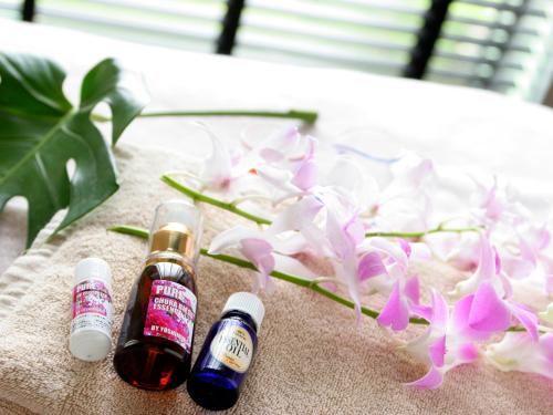 two bottles of essential oils next to a flower at Laguna Garden Hotel in Ginowan