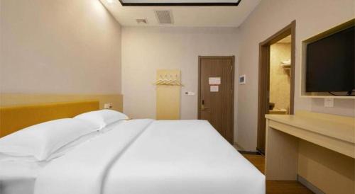 a bedroom with a white bed and a flat screen tv at 7Days Premium Yichang Railway Station East in Yichang