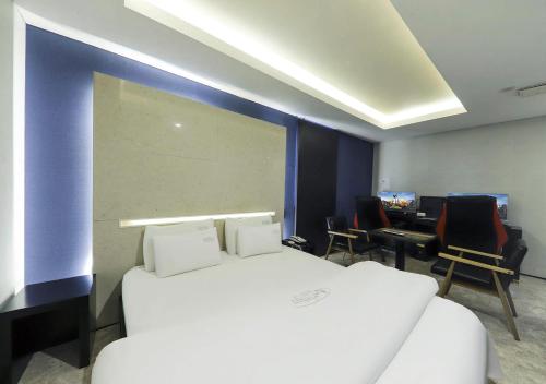 a room with a bed and chairs and a desk at Arieti A in Gimhae