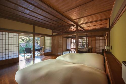 a bedroom with a large white bed in a room with windows at Ochiairo in Izu